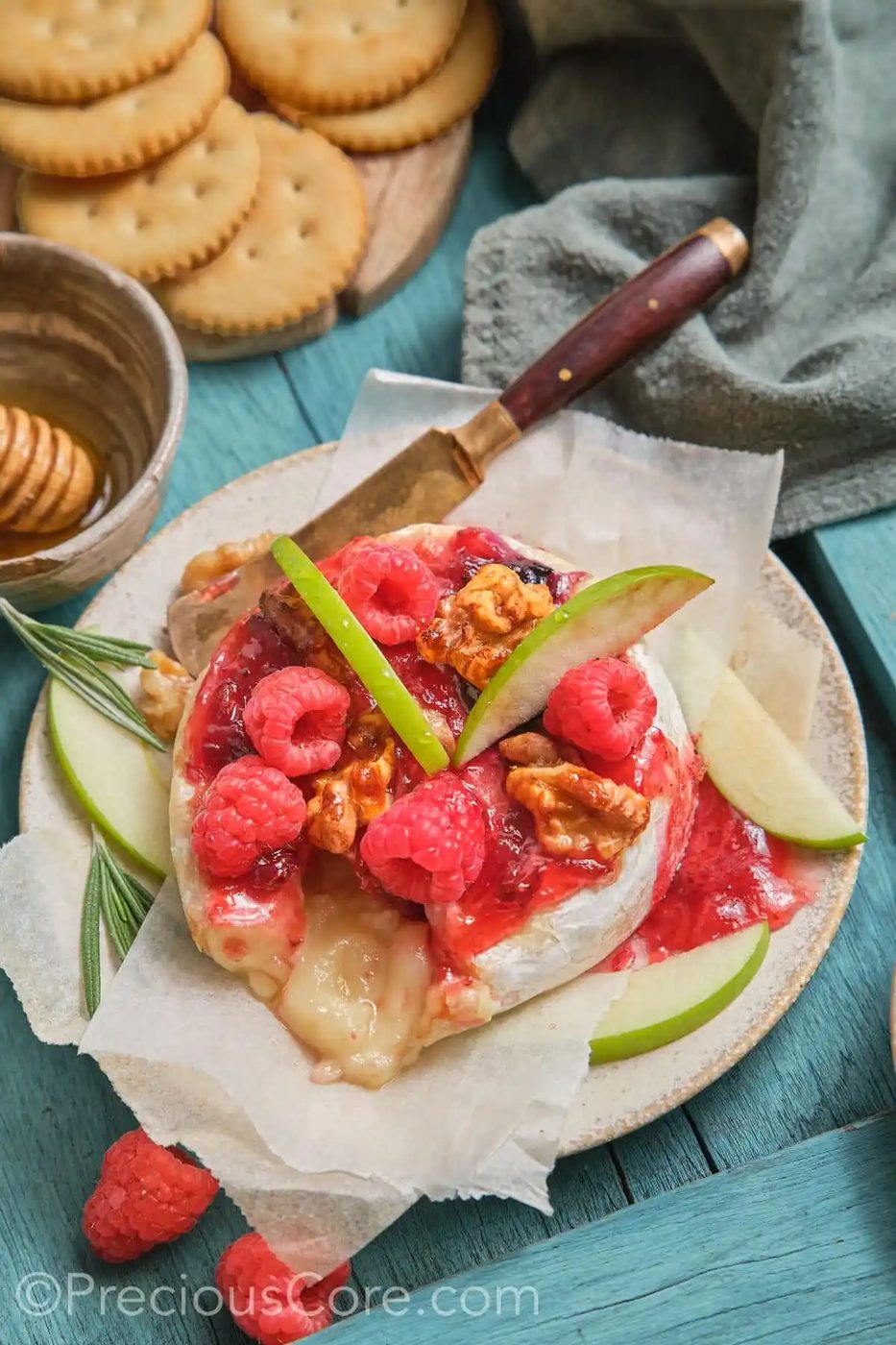 Around baked brie topped with preserves, fresh fruit, and candied walnuts.