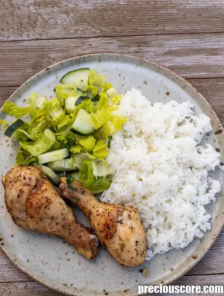 Chicken drumsticks, rice and lettuce on a plate.