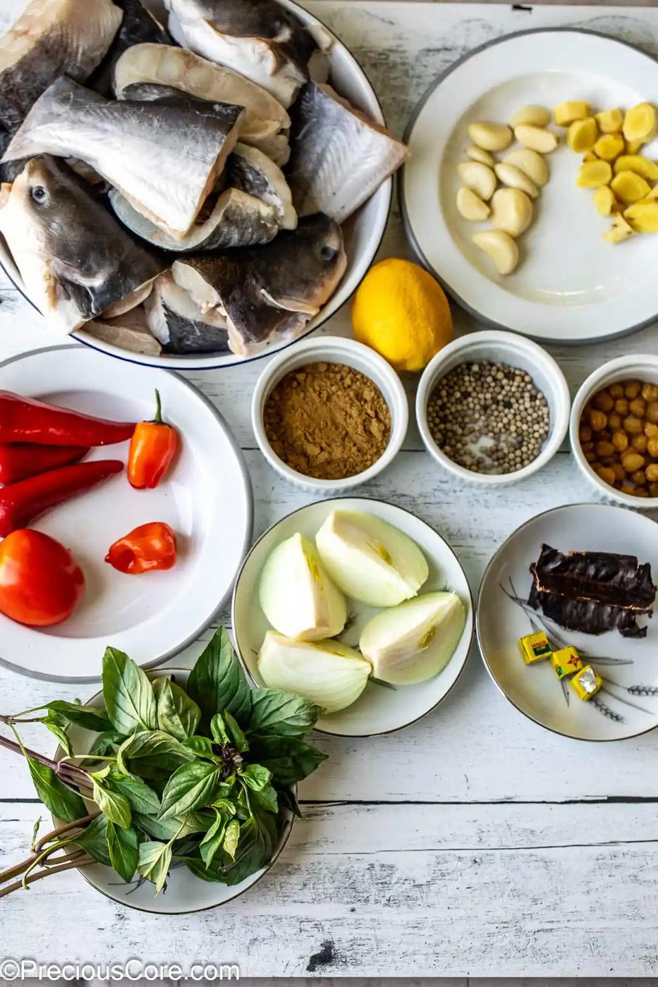 All ingredients for catfish pepper soup on a white surface.