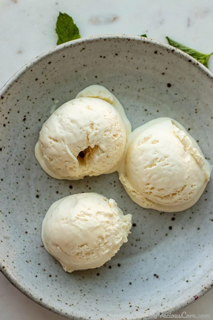 3 scoops of homemade vanilla ice cream in a bowl.