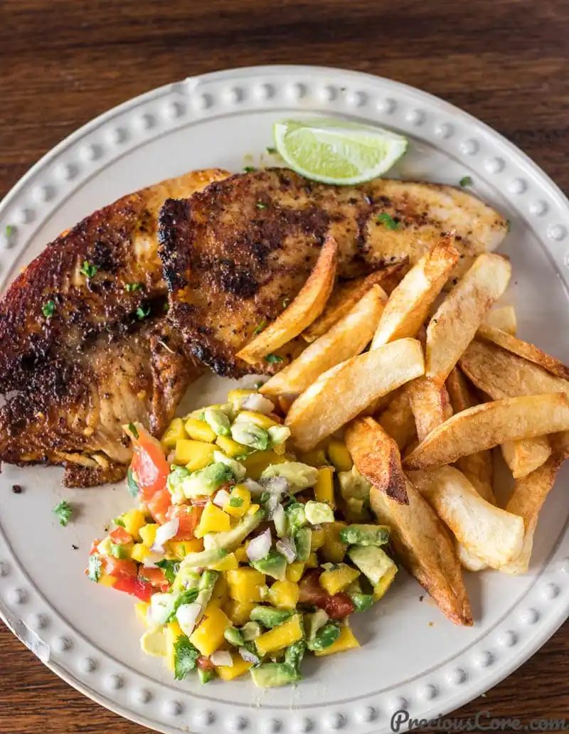 Grilled fish and a lime wedge with mango avocado salsa.