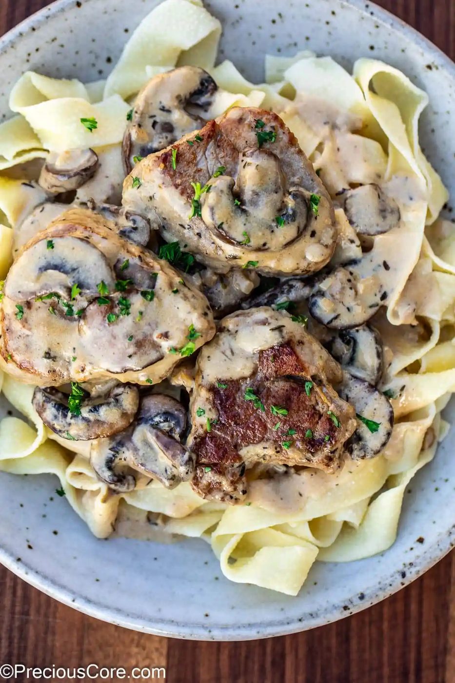 Pork tenderloin in creamy mushroom sauce and pasta in a bowl.