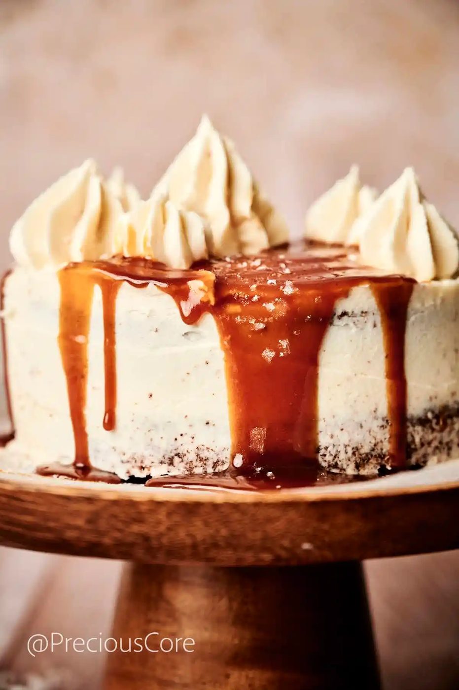 Salted Caramel Cake on a cake stand with caramel dripping down the sides.