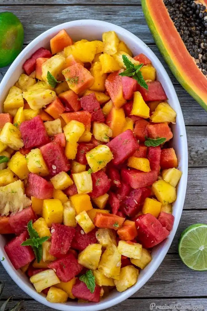 fruit salad in bowl, half a papaya and lime nearby