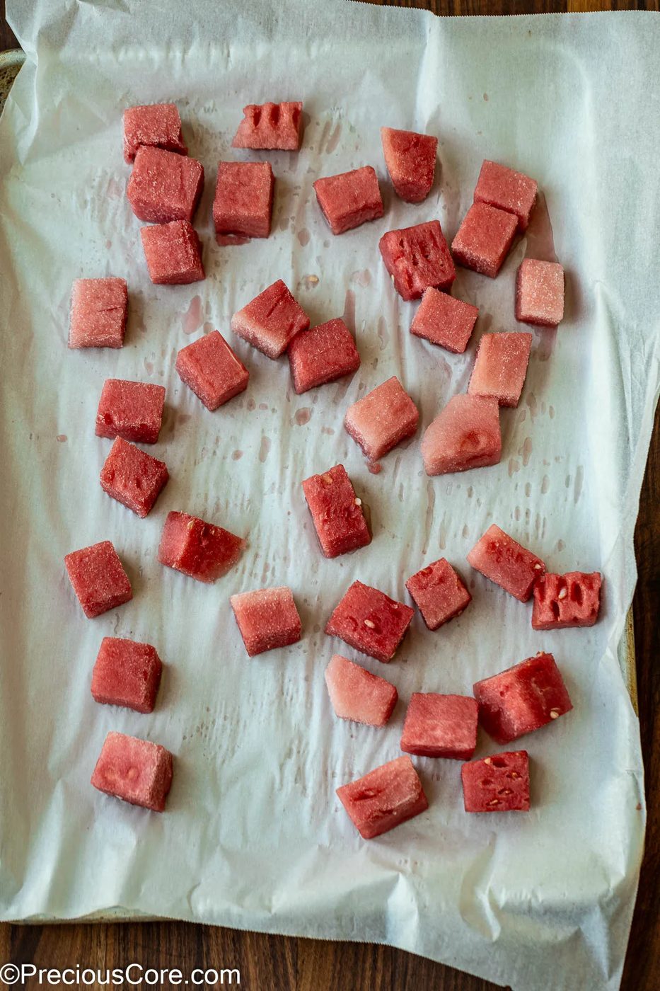 Watermelon cubes on a parchment-lined sheet pan.
