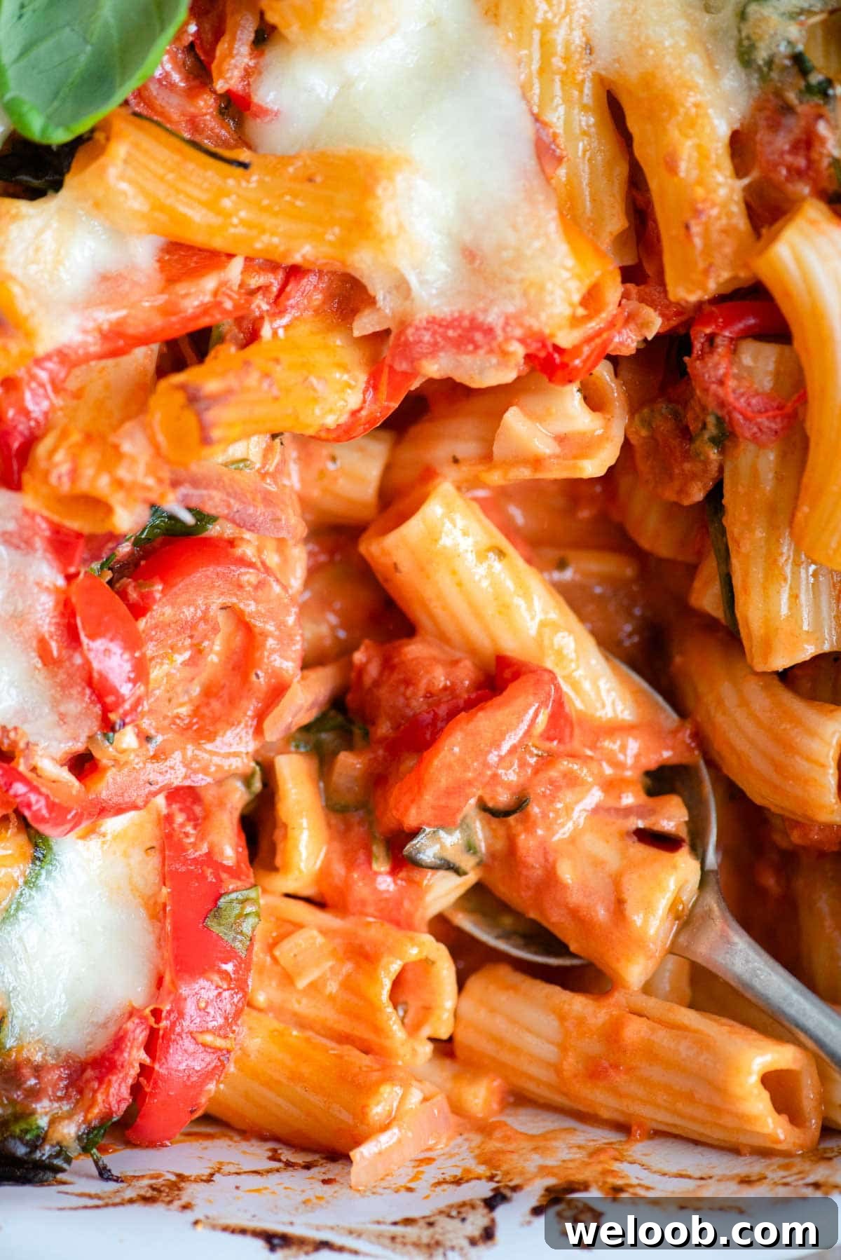 A close up of baked ziti with vegetables in a tomato sauce