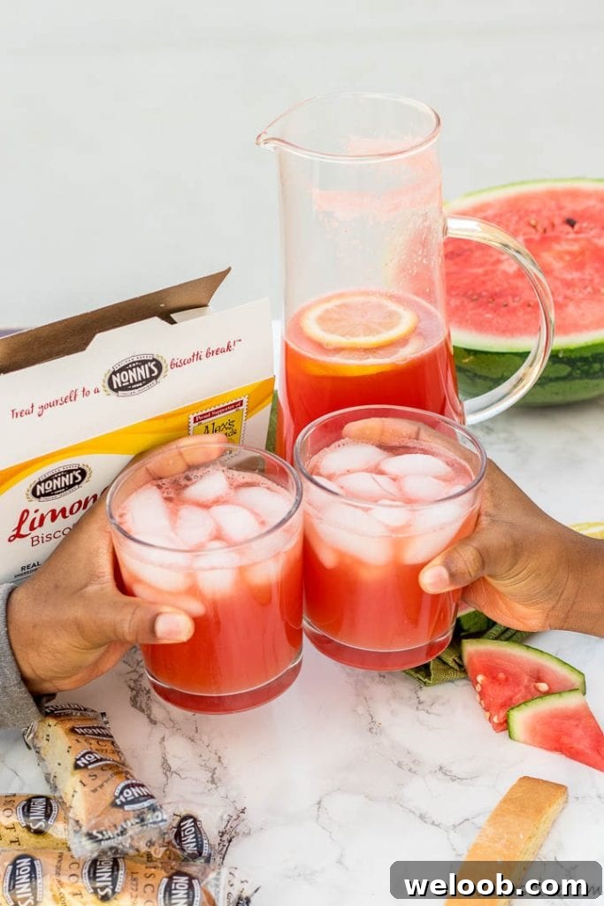 Two hands holding cups of fresh watermelon lemonade