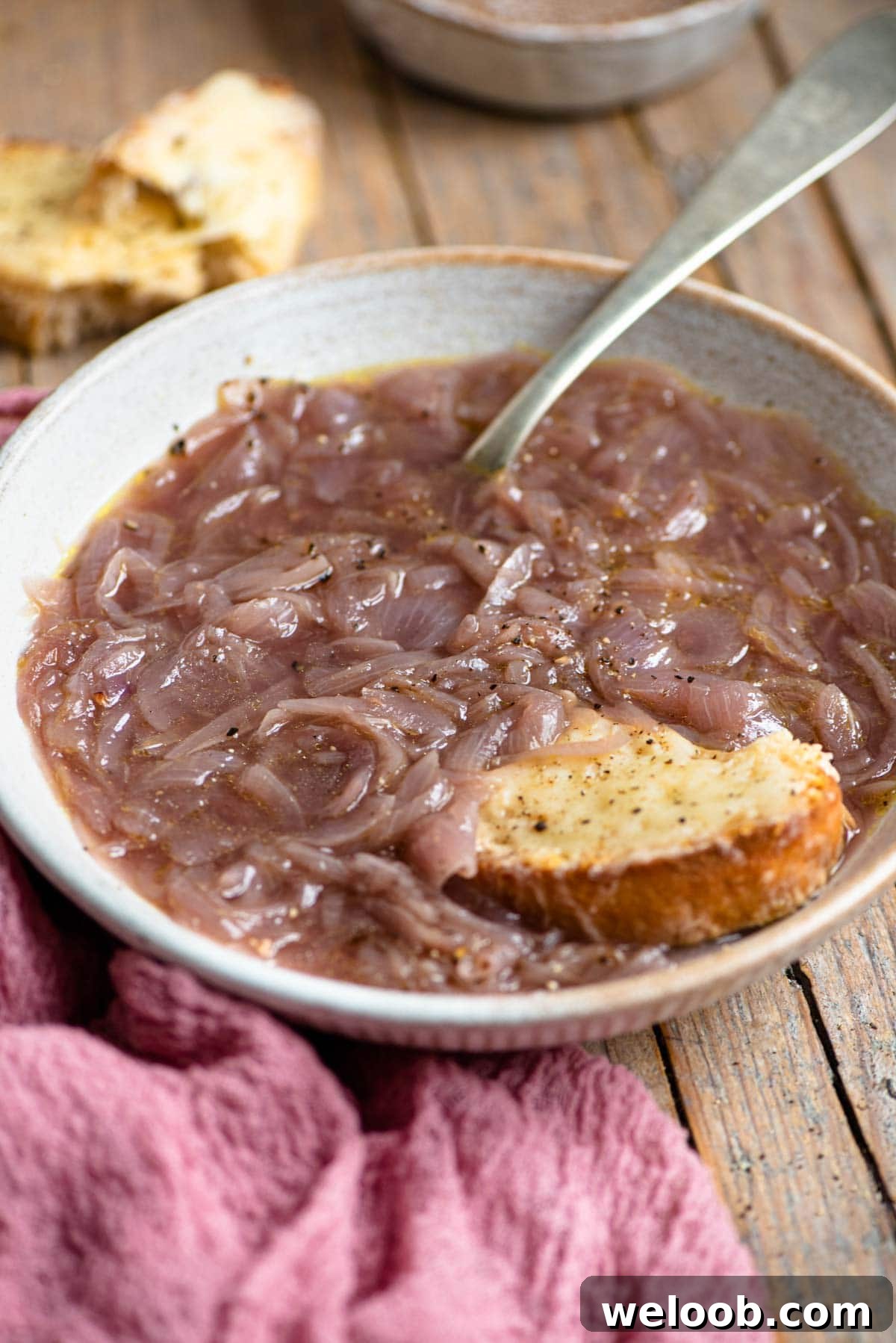 A bowl of Carabaccia onion soup with a piece of cheesy bread at the side