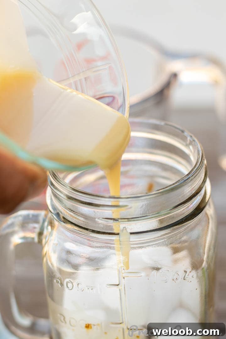 Sweetened condensed milk pouring into coffee cup