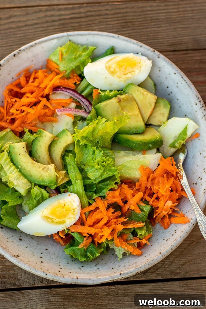 A serving of lettuce salad in a bowl with lemon dressing drizzled on top.