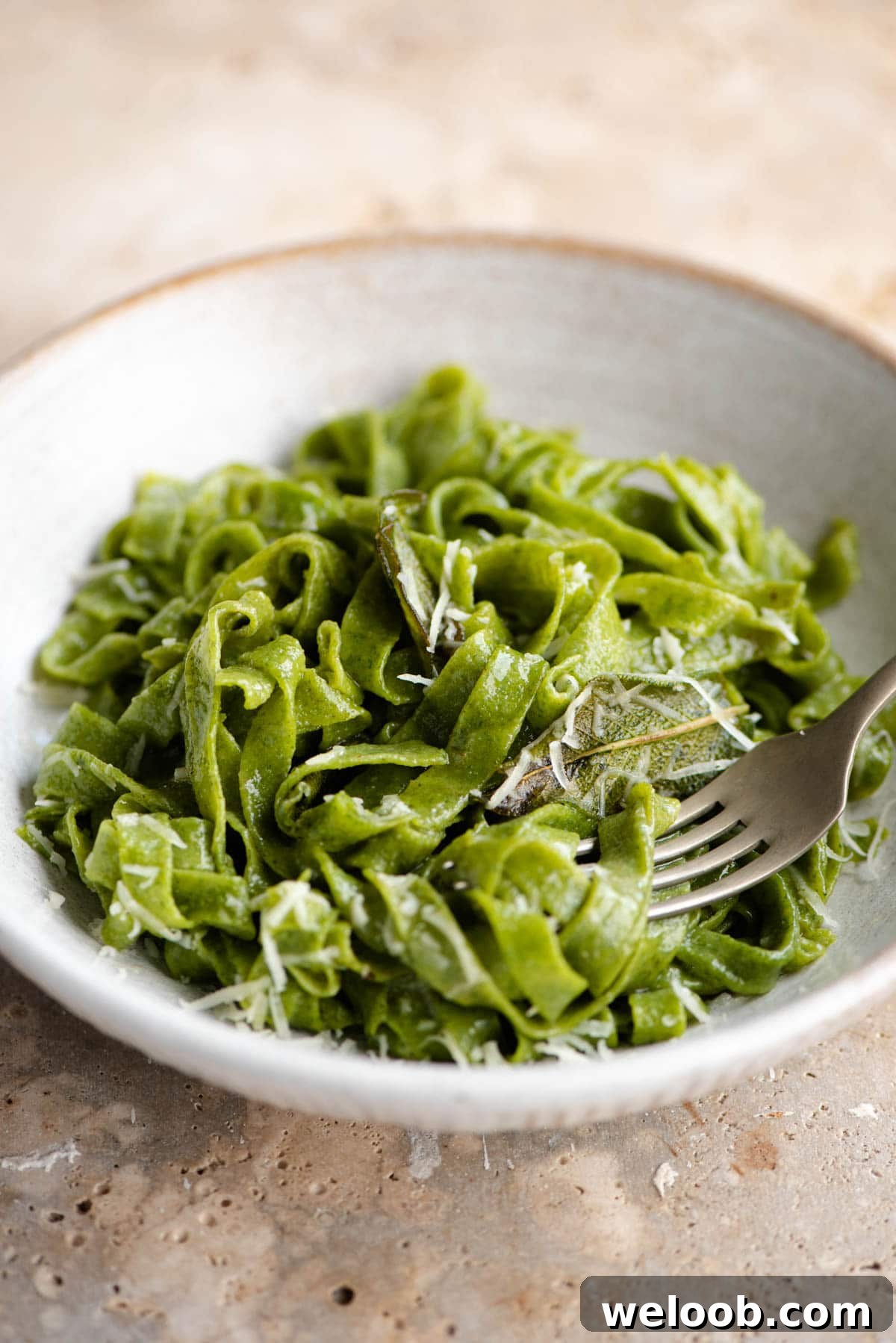 A close up of cooked spinach pasta in a bowl