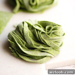 A close up of spinach pasta tagliatelle on a marble cutting board