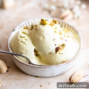 Three scoops of pistachio ice cream in a small bowl with a spoon
