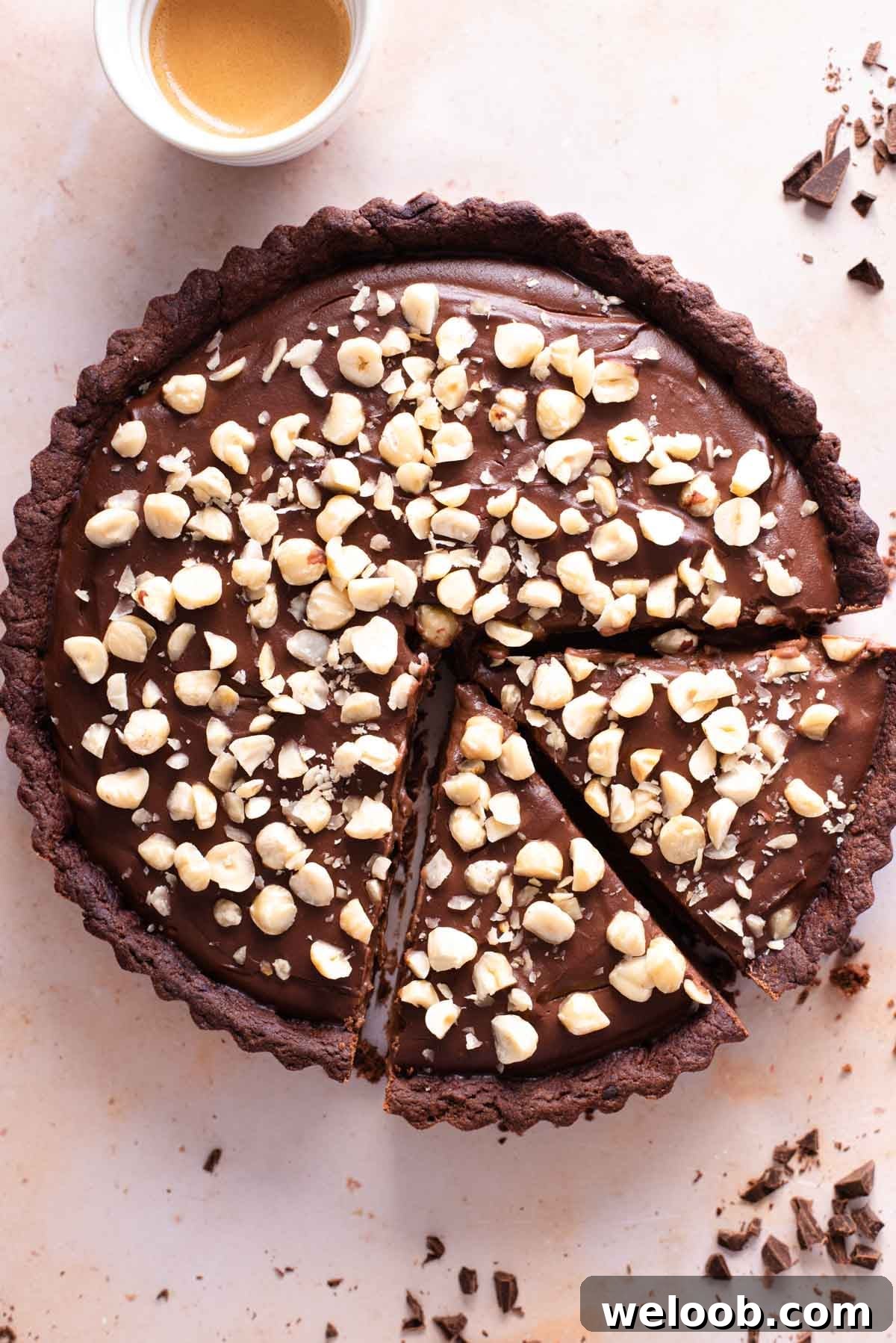 An overhead shot of a chocolate tart topped with hazelnuts