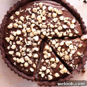 A close up of a chocolate tart topped with chopped hazelnuts