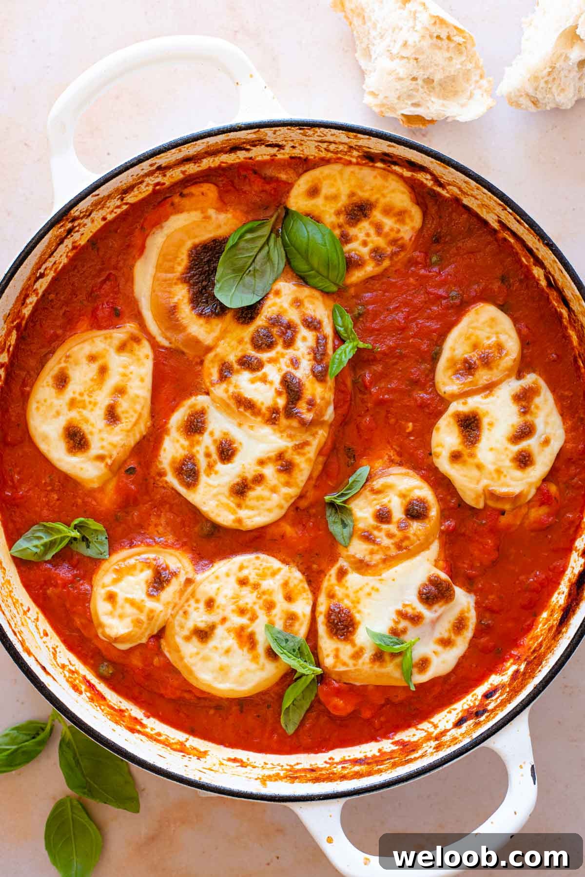Smoked Scamorza Chicken Pizzaiola with Tomato and Herbs 8 An overhead shot of a chicken pizzaiola in a large pan topped with fresh basil