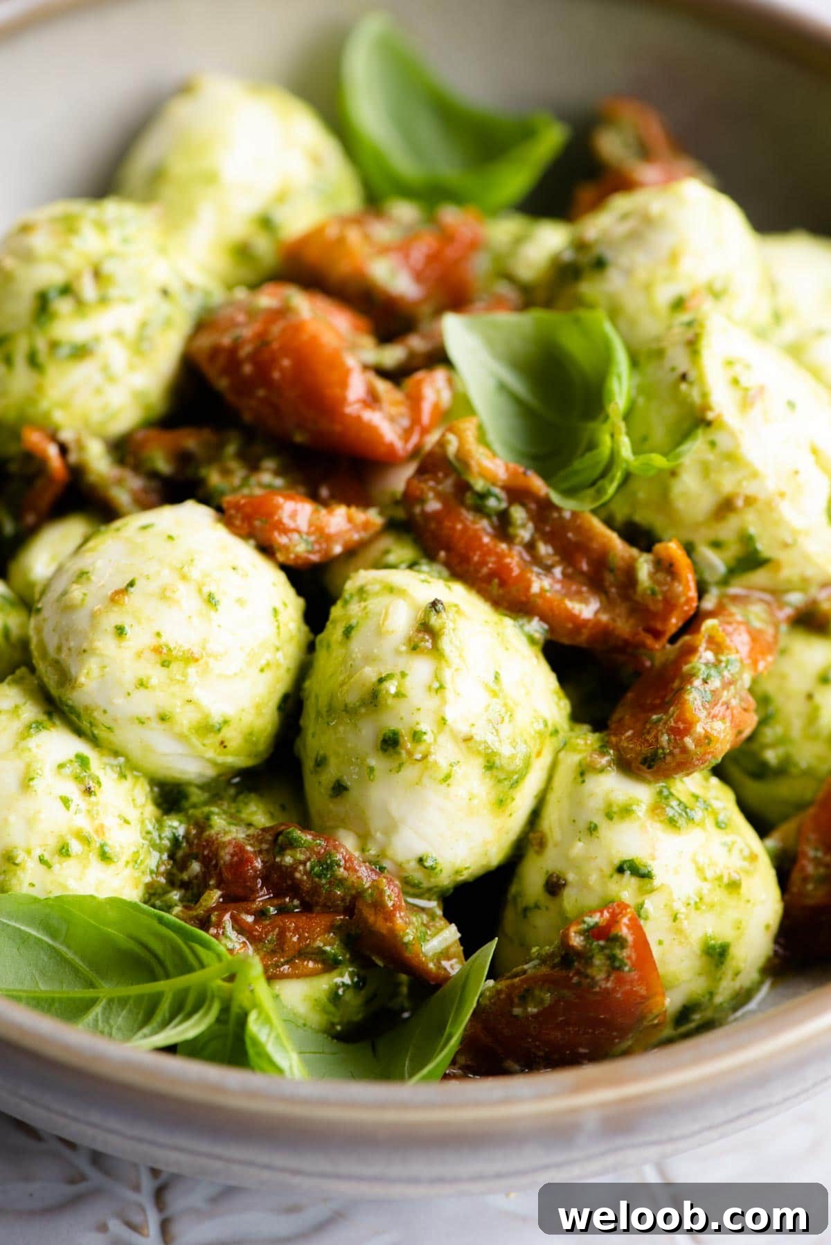 A close up of mozzarella bocconcini balls with tomatoes and pesto