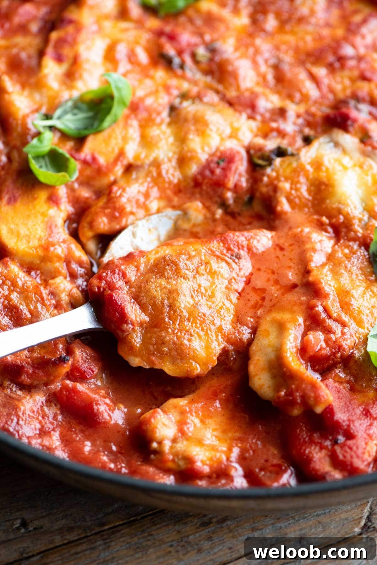 A close up of a piece of chicken sorrentina on a serving spoon