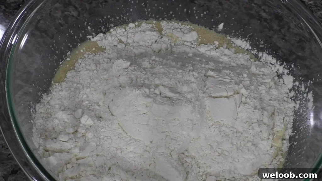flour in a bowl with wet ingredients for dinner rolls