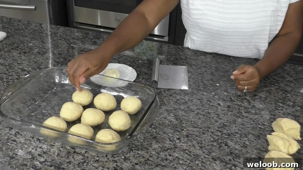 Hand placing balls of dough into a baking dish
