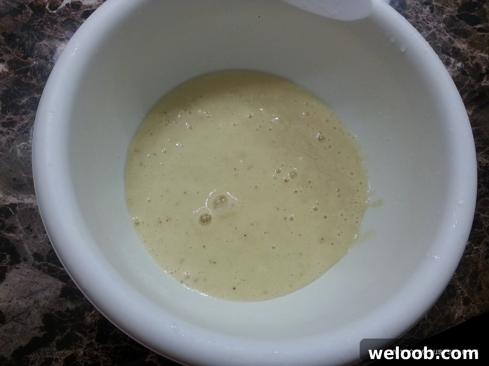 Banana and liquid in a mixing bowl.