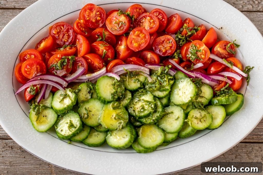 tomato cucumber salad with dressing drizzled on top