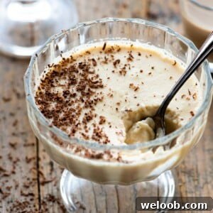A close up of baileys panna cotta in a small glass bowl with a spoon in it