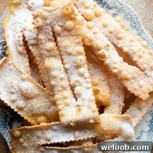 An overhead shot of cenci fried pastries on a plate dusted with sugar