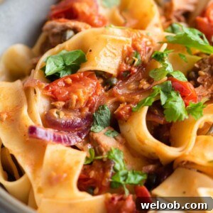 A close up of tuna pasta with tomatoes and parsley