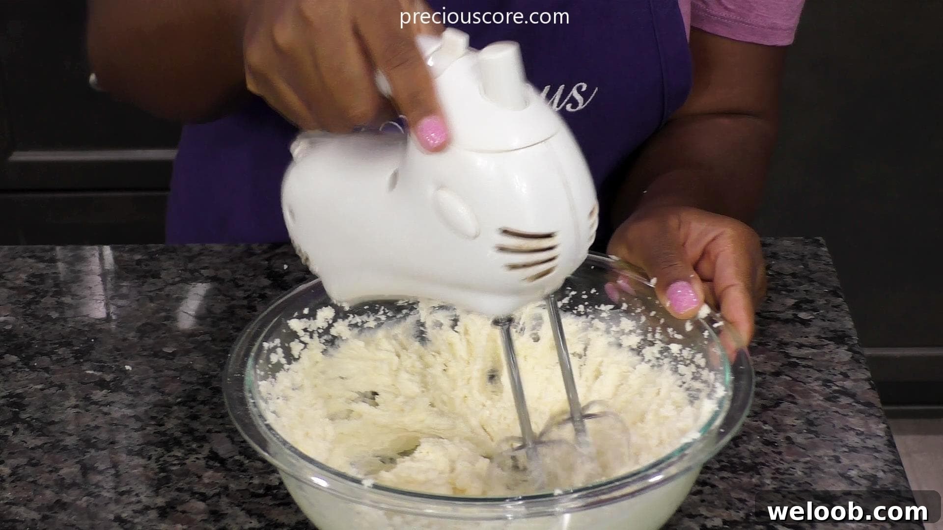Hand holding electric beater beating butter and sugar