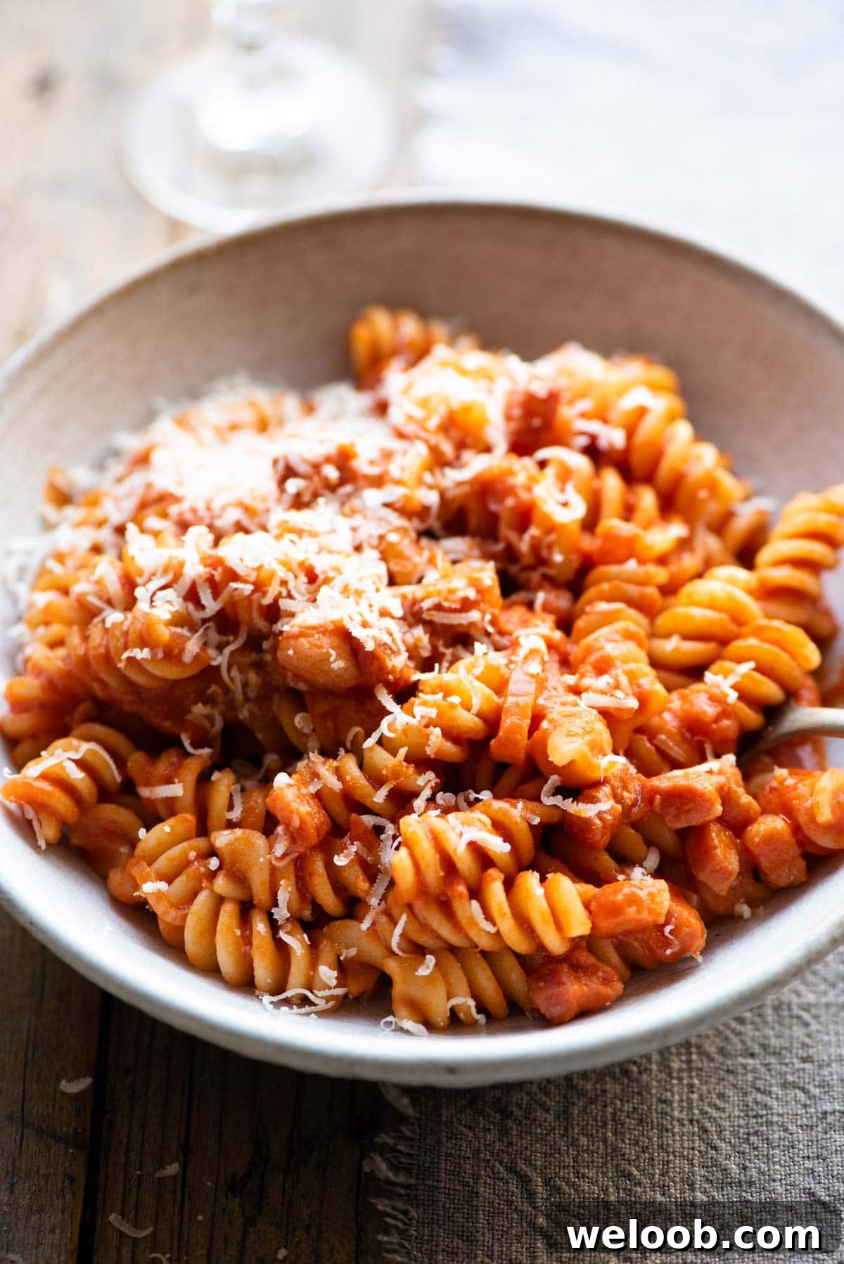 A close up of creamy tomato pasta in a bowl topped with parmesan