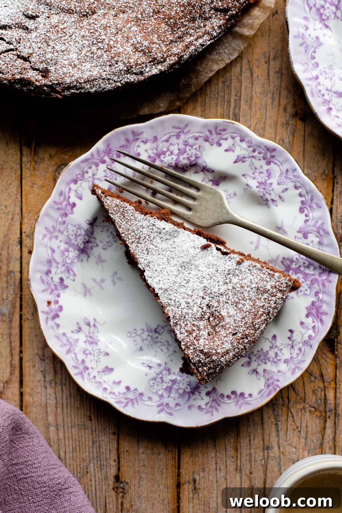 An overhead shot of a slice of chocolate torta caprese on a pink patterned plate