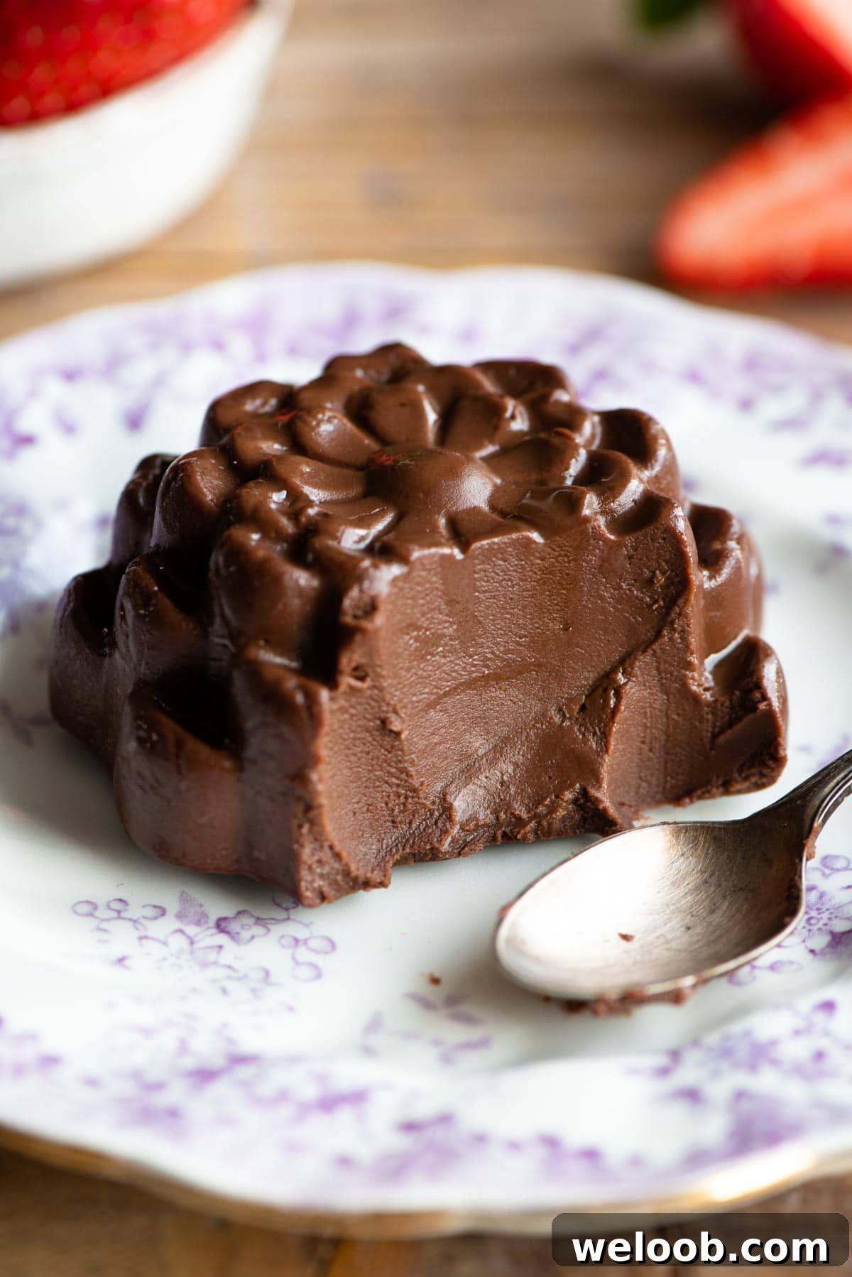 A close up of a chocolate budino with a bite out sitting on a small white plate