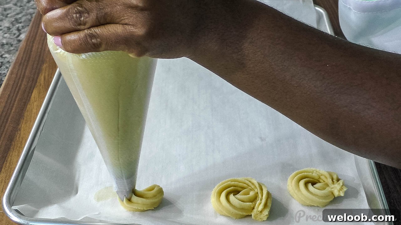 Hand piping butter cookies unto baking sheet