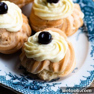A close up of a Zeppole (Italian pastry) topped with custard and a cherry on top sitting on a blue plate