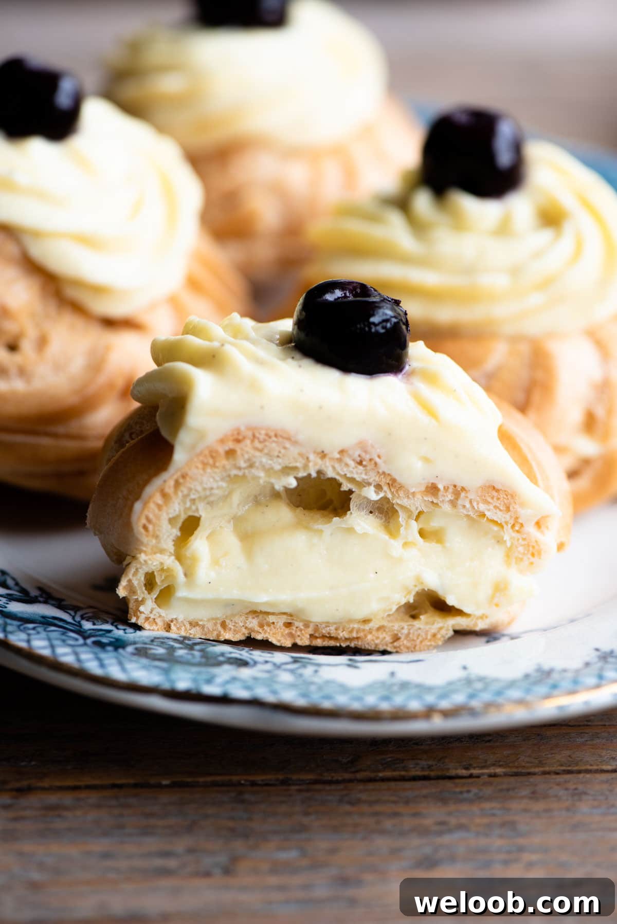 A close up of an Italian pastry cut in half and filled with pastry cream sitting on a blue plate.