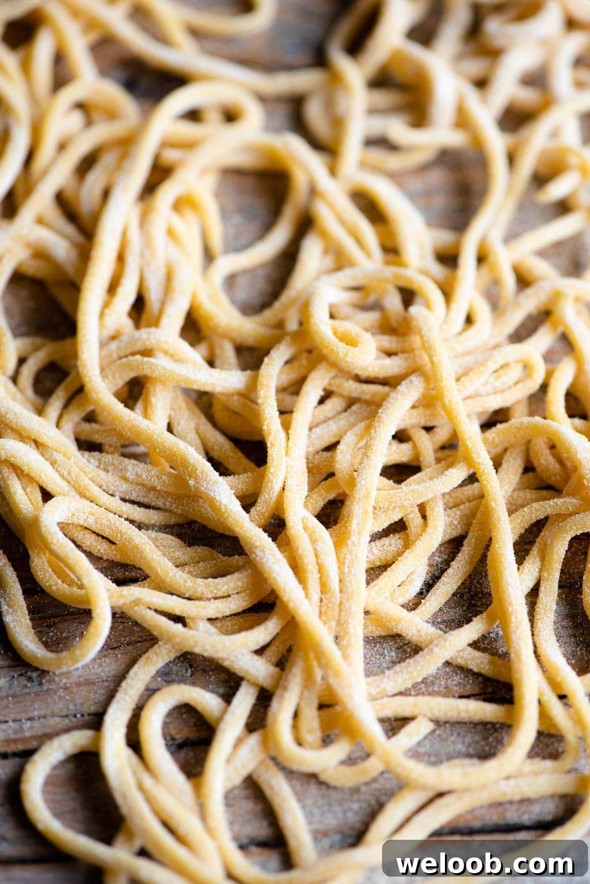 A close up of Tonnarelli pasta aka Spaghetti alla Chitarra scattered on a wooden surface
