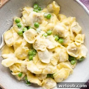 A close up of Tortellini alla Panna in a bowl with peas