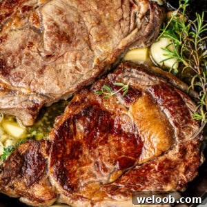 Perfect Pan-Seared Ribeye Steak with Crispy Crust and Juices 16 Two ribeye steaks in a cast iron skillet with rosemary, thyme, and garlic.