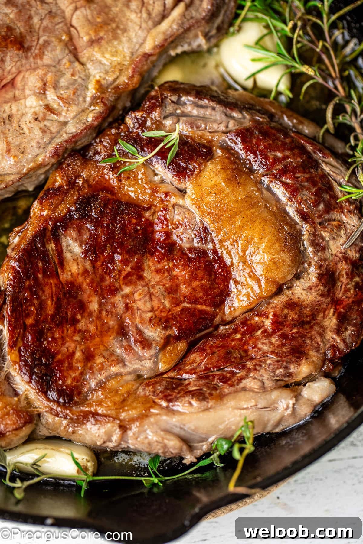 Perfect Pan-Seared Ribeye Steak with Crispy Crust and Juices 3 Close up shot of a pan seared ribeye with fat marbling.