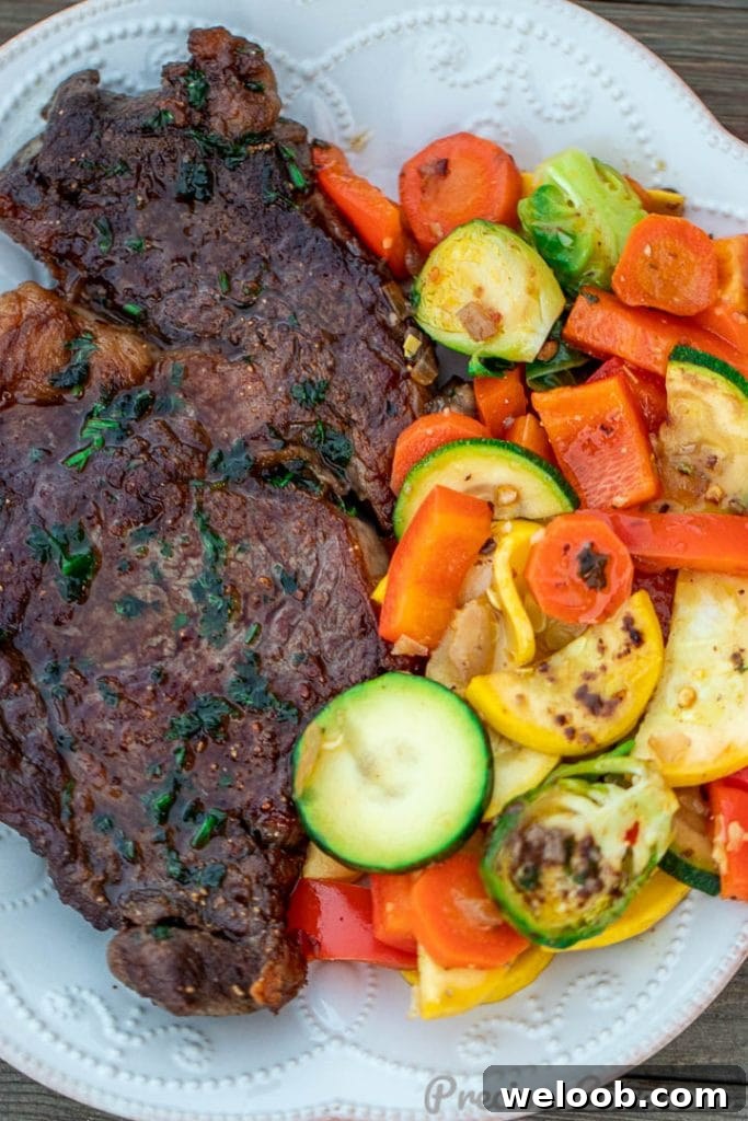 Perfect Pan-Seared Ribeye Steak with Crispy Crust and Juices 8 Pan seared steak and sautéed veggies on a white plate.