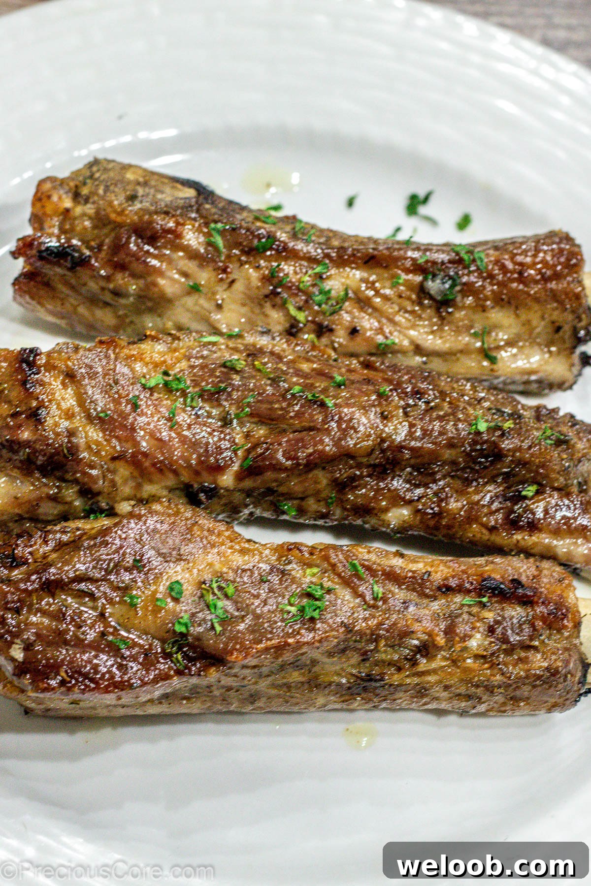 3 baked ribs on a white plate.