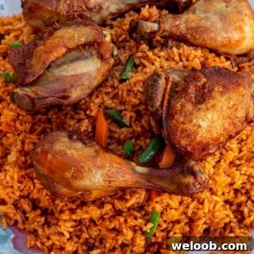 Jollof Rice on a serving platter with cooked chicken thighs and drumsticks on top