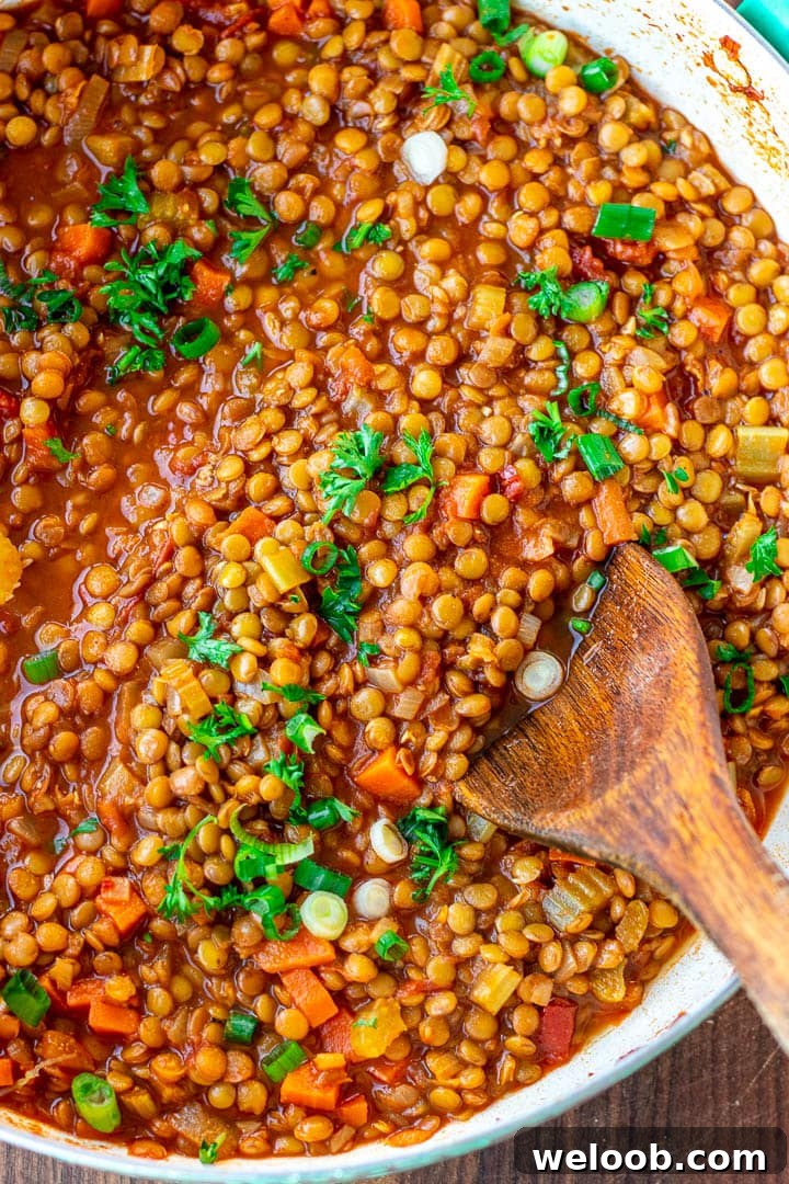 A pot of Lentil Stew garnished with chopped fresh parsley and green onions