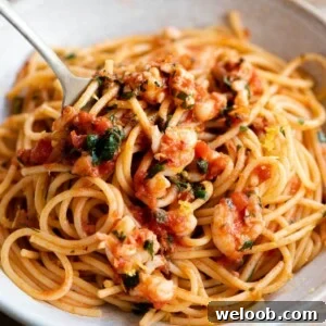A close up of a fork in a bowl or shrimp spaghetti.