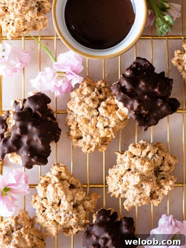 An overhead shot of both original and chocolate Brutti ma Buoni cookies on a gold cooling rack with pink flowers dotted around