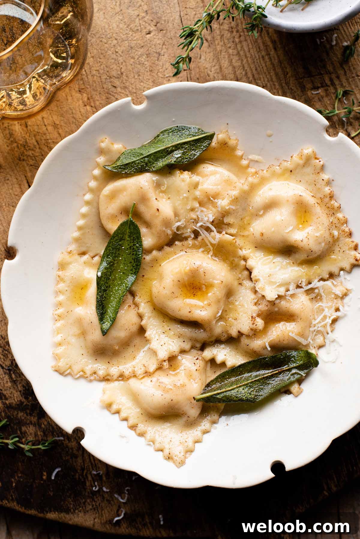 An overhead shot of butternut squash ravioli in a white bowl sitting on a wooden serving board.
