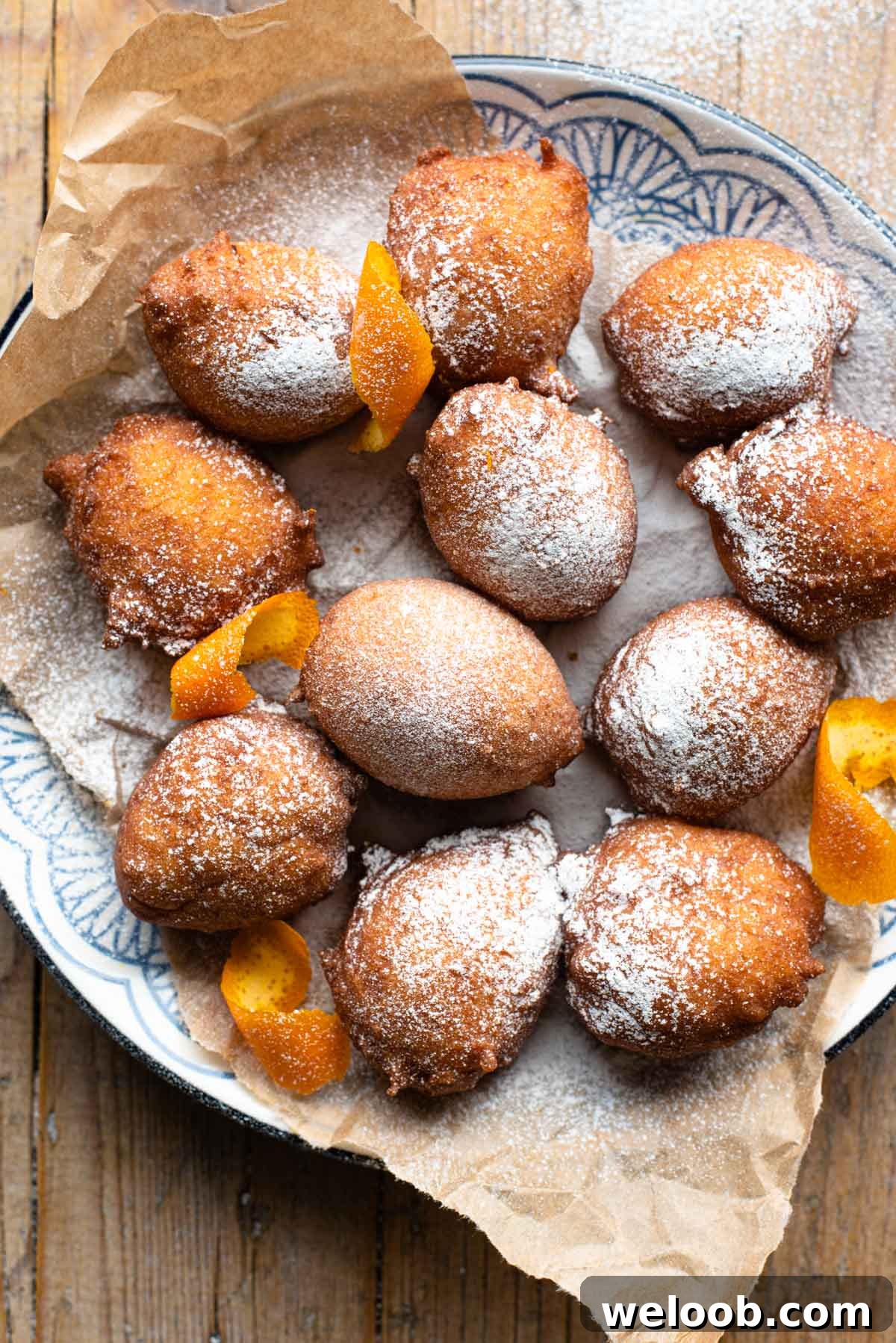 An overhead shot of small ricotta doughnuts on a plate dusted with powdered sugar