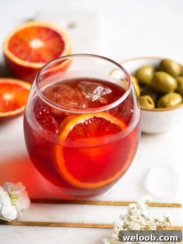 A close up of a Negroni Sbagliato cocktail with olives at the side