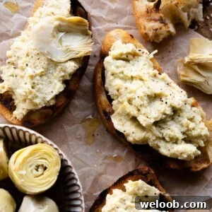 A cropped close up of 3 pieces of artichoke bruschetta sitting on baking parchment.
